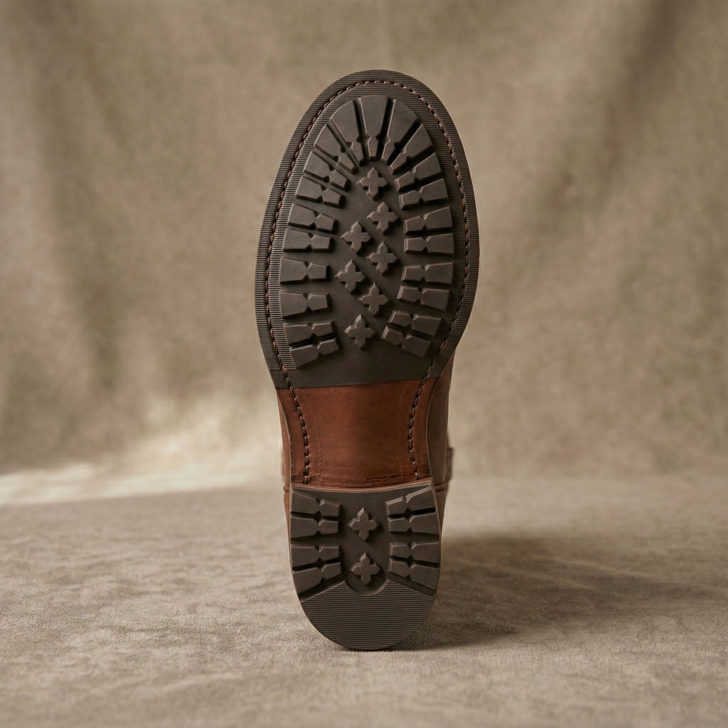 Brown leather boot sole on a textured beige background