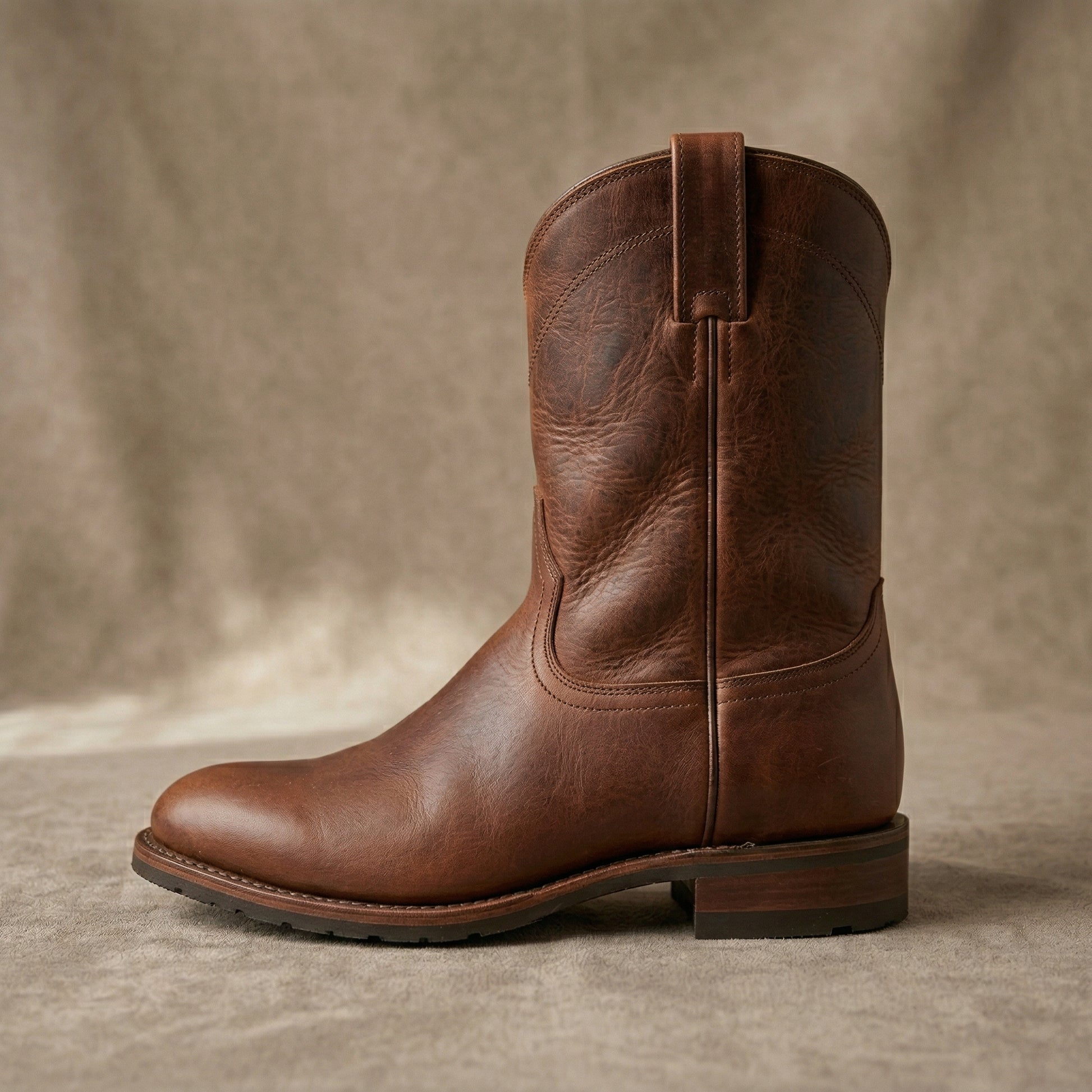 Brown leather boot on a textured surface with a neutral background