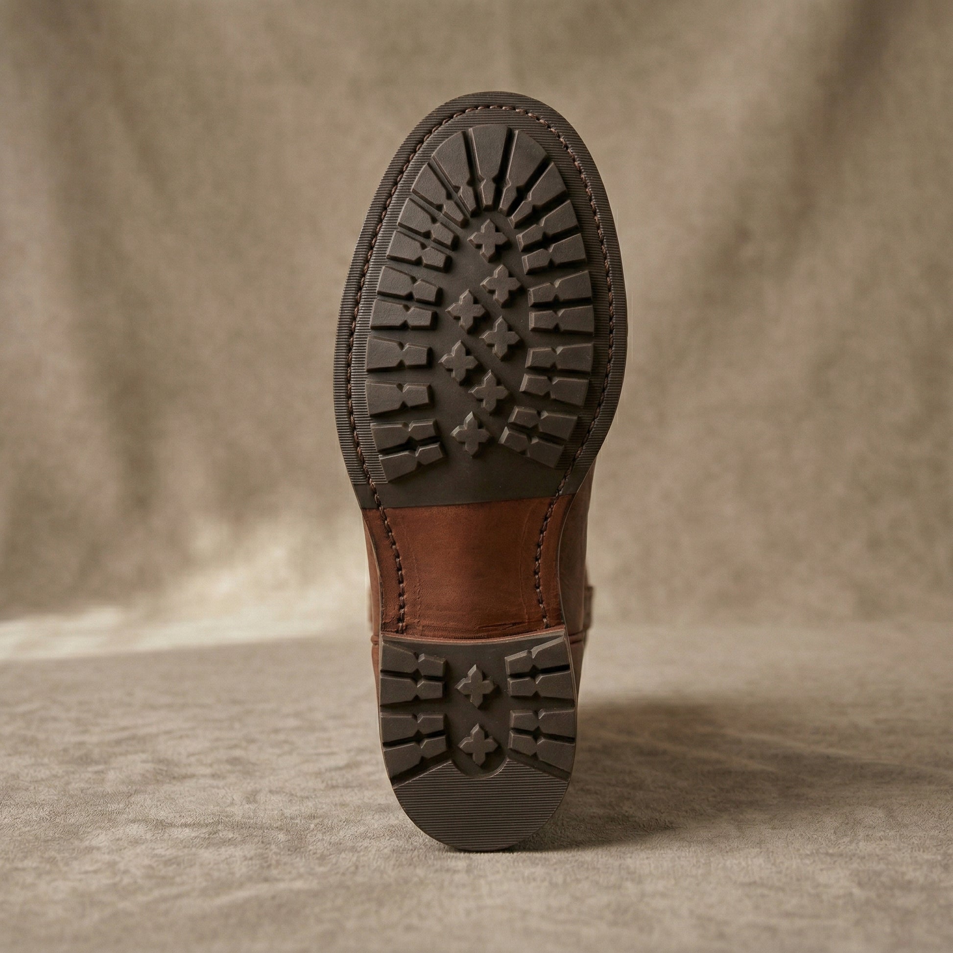 Brown leather boot sole on a textured beige background