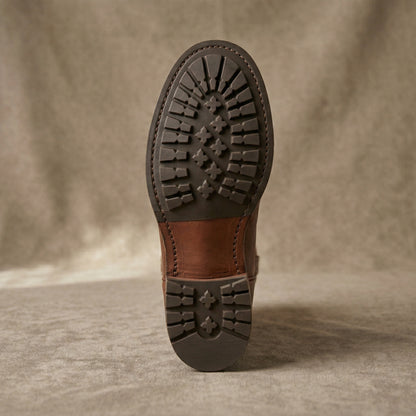Brown leather boot sole on a textured beige background
